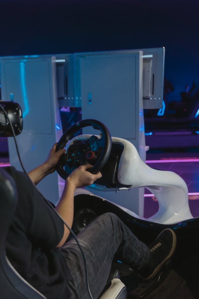 Person using a VR headset and gaming steering wheel for a racing simulation indoors.